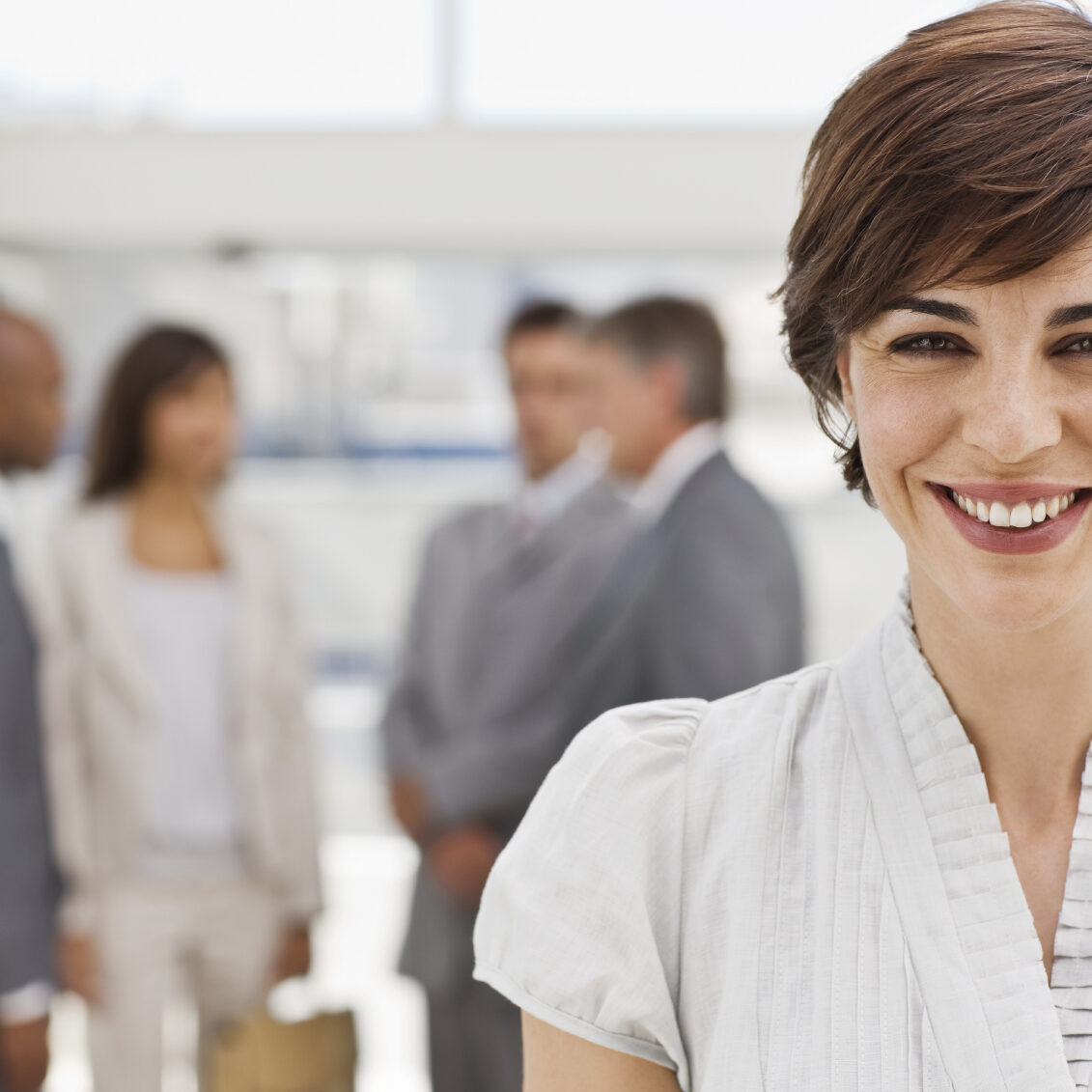 Closeup portrait of happy businesswoman with colleagues in the background